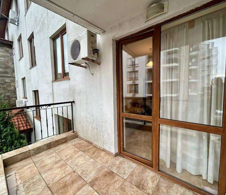 Balcony view of a furnished studio apartment in Apollon, Ravda, with glass door and curtain.