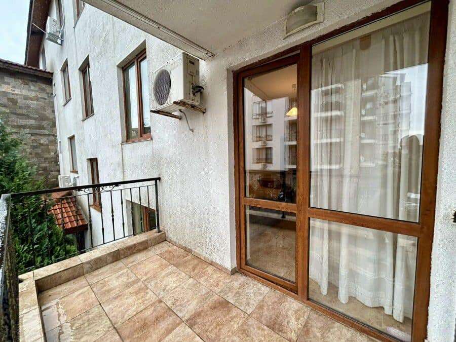 Balcony view of a furnished studio apartment in Apollon, Ravda, with glass door and curtain.
