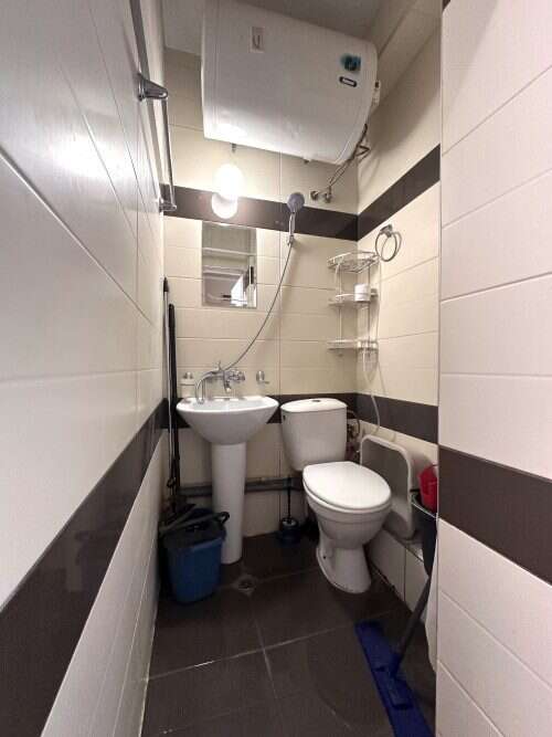 Compact bathroom with sink, toilet, and shower in a small, well-maintained space.