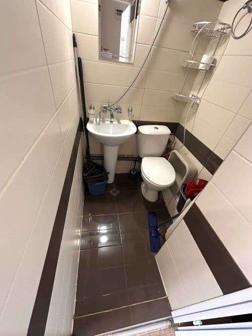 Small bathroom with sink, toilet, and shower in a compact studio apartment.