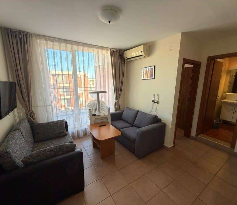 Bright living room with large window and balcony access, featuring modern furniture and air conditio.