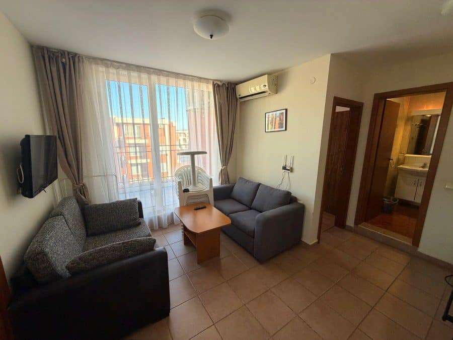 Bright living room with large window and balcony access, featuring modern furniture and air conditio.