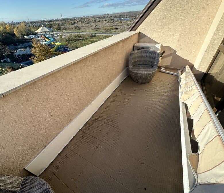 Balcony of a furnished studio apartment with seating and scenic landscape view.
