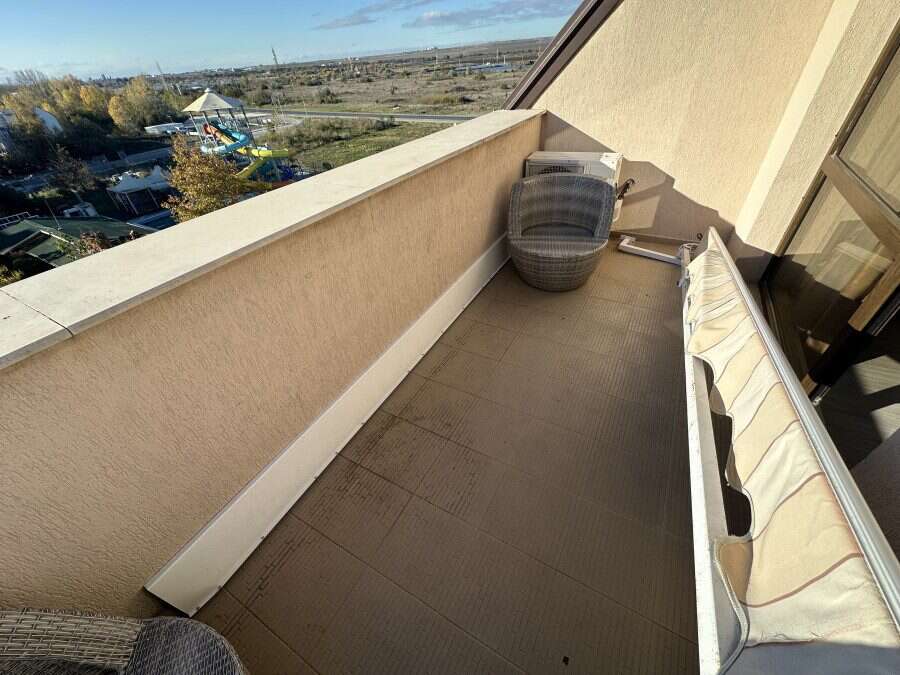 Balcony of a furnished studio apartment with seating and scenic landscape view.