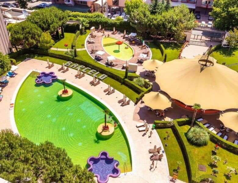 Pool area with sun loungers, umbrellas, and lush greenery at Barcelo Royal Beach.