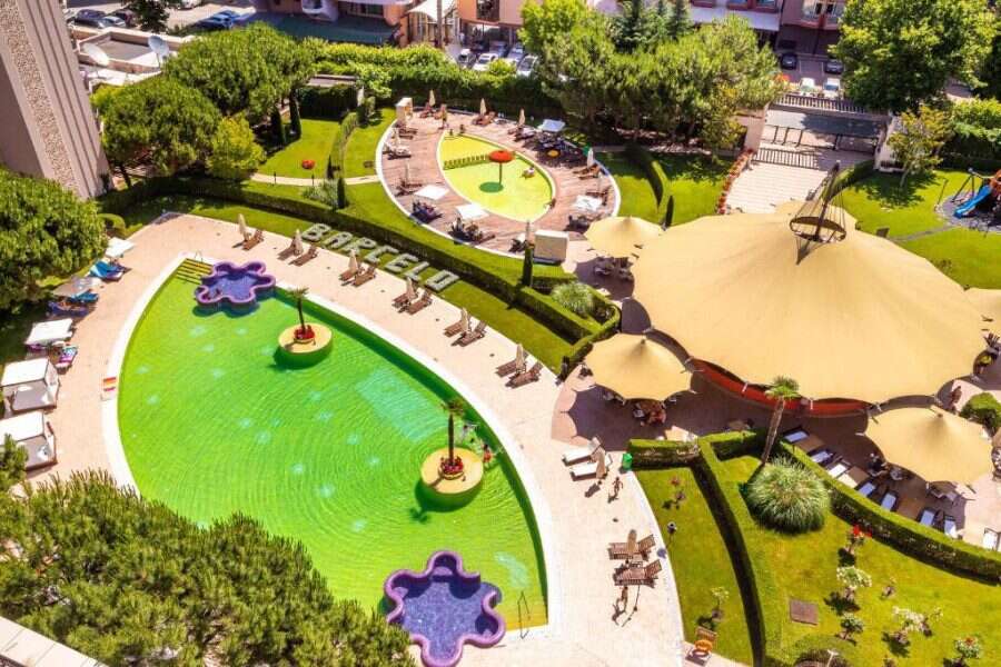 Pool area with sun loungers, umbrellas, and lush greenery at Barcelo Royal Beach.