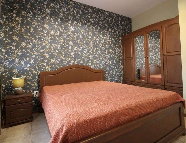 Comfortable bedroom with floral accent wall and wooden furniture in Sveti Vlas.