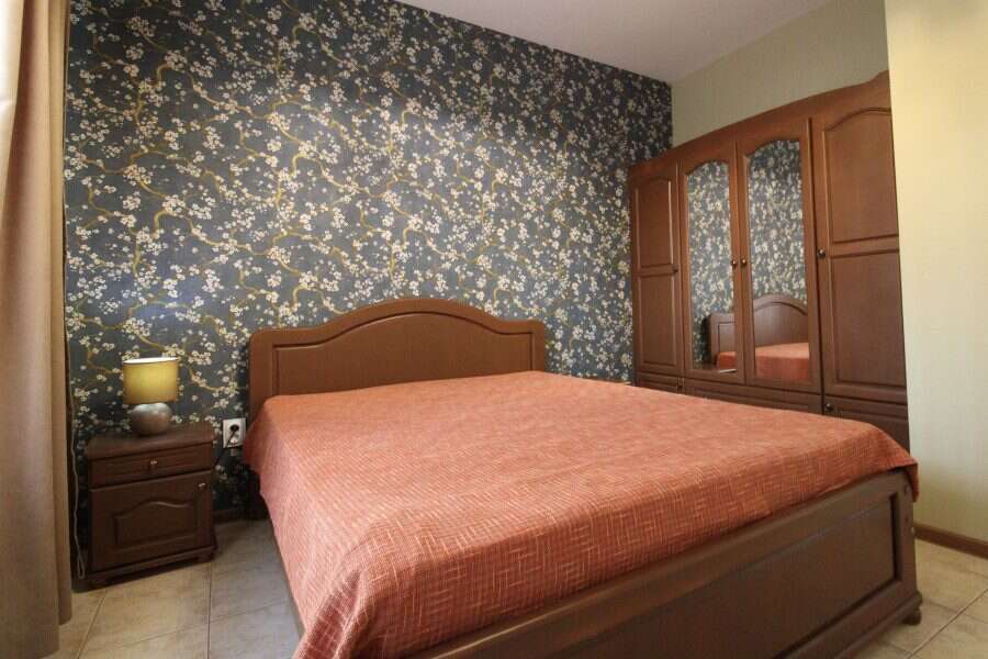 Comfortable bedroom with floral accent wall and wooden furniture in Sveti Vlas.