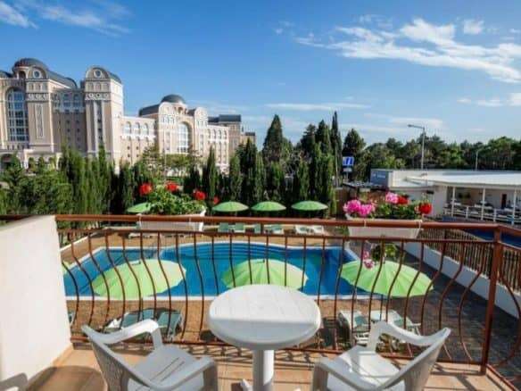 Balcony overlooking a swimming pool with lush greenery and colorful flowers in Sveti Vlas, near the.