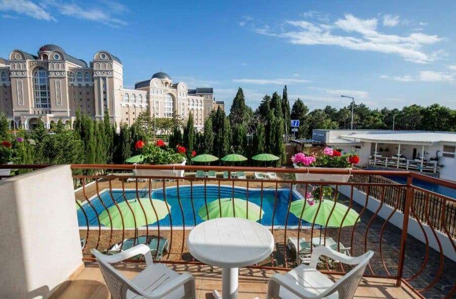 Balcony overlooking a swimming pool with lush greenery and colorful flowers in Sveti Vlas, near the.