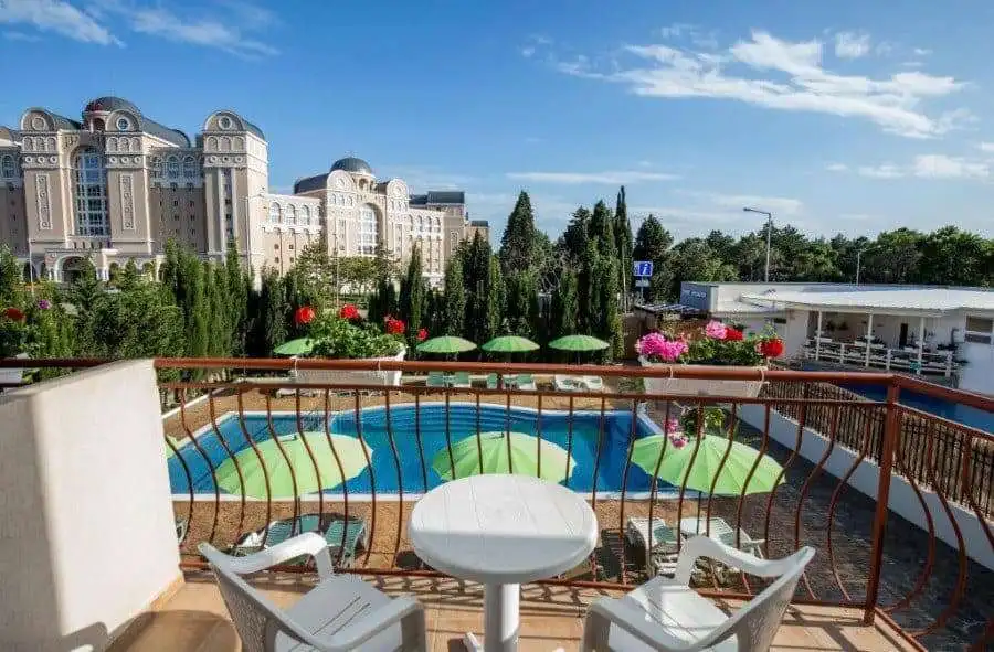 Balcony overlooking a swimming pool with lush greenery and colorful flowers in Sveti Vlas, near the.