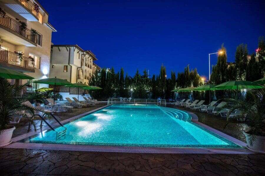 Brightly lit swimming pool surrounded by sun loungers and umbrellas in Sveti Vlas.