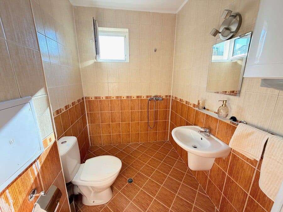 Bathroom with toilet, sink, and mirror in a bright, clean space.
