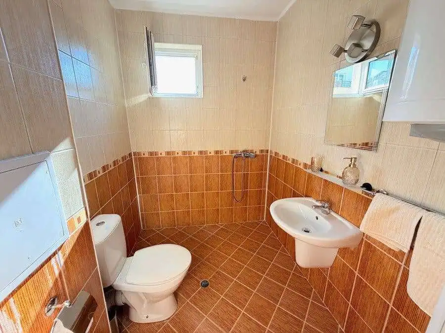 Bathroom with toilet, sink, and mirror in a bright, clean space.