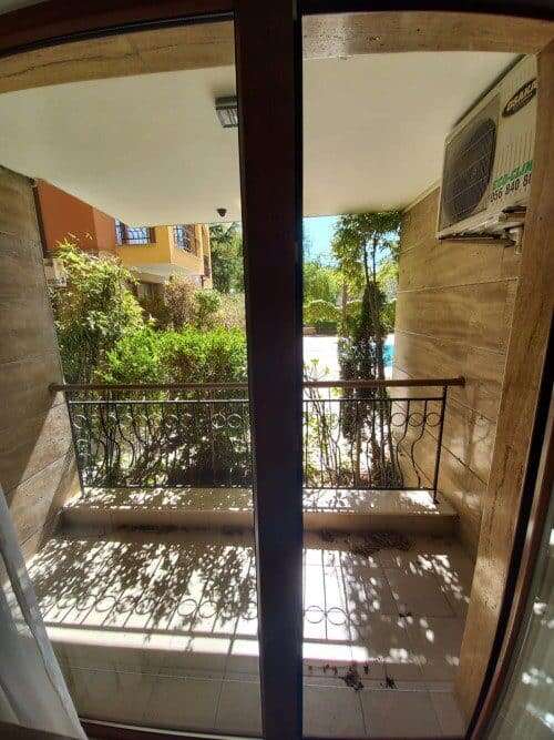 Balcony view of lush greenery and outdoor space from a 1-bedroom apartment.