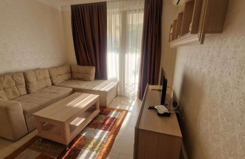 Bright living room with sofa and TV in Harmony Suites apartment, near Sunny Beach, Bulgaria.