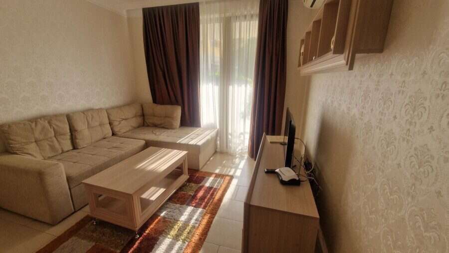 Bright living room with sofa and TV in Harmony Suites apartment, near Sunny Beach, Bulgaria.