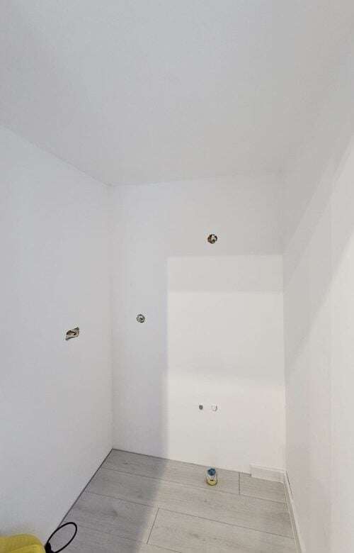 Interior view of a white-walled room with electrical outlets in a refurbished bungalow.