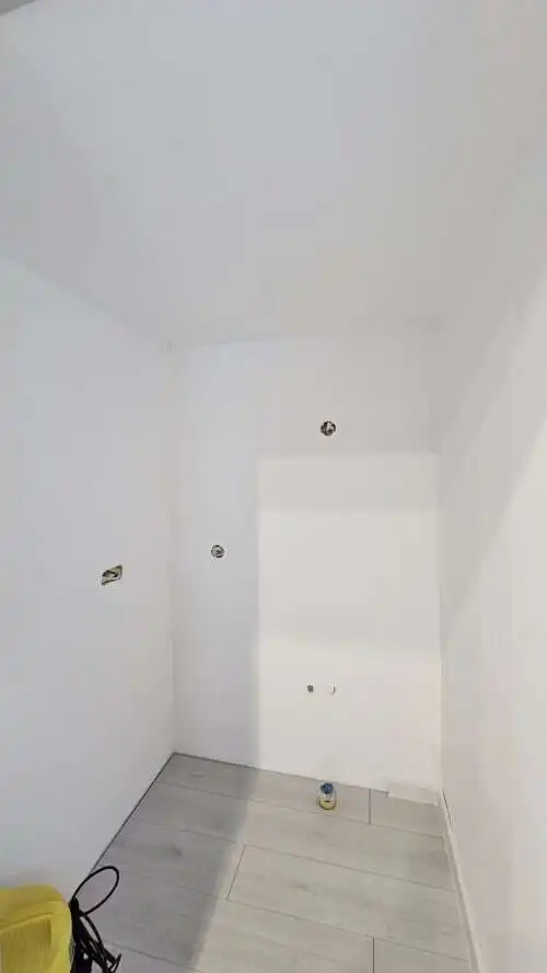 Interior view of a white-walled room with electrical outlets in a refurbished bungalow.