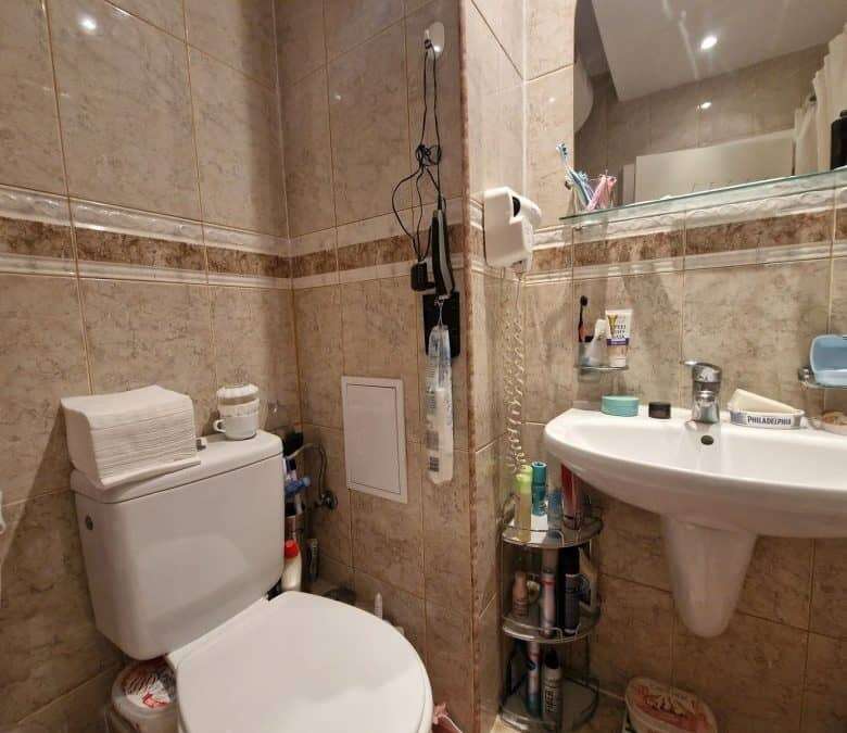 Compact bathroom with toilet and sink in a seaside studio.