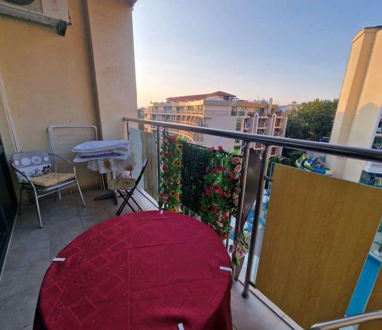 Balcony with cityscape view, outdoor seating, and decorative plants in a modern apartment.