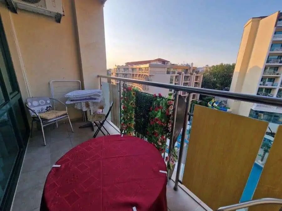 Balcony with cityscape view, outdoor seating, and decorative plants in a modern apartment.