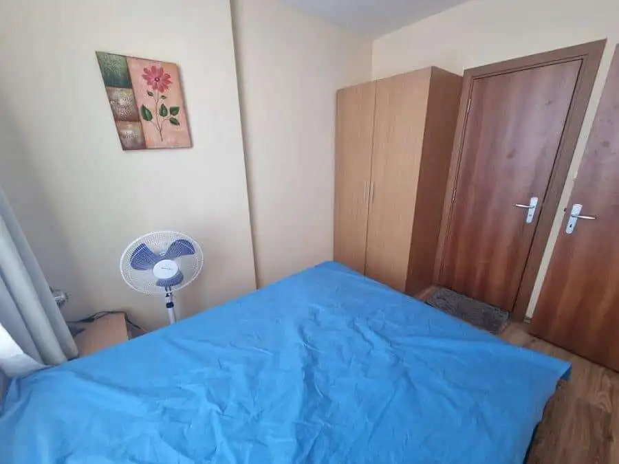 Interior view of a 1-bedroom apartment in Dawn Park, Sunny Beach with a blue bed and wooden furnitur.