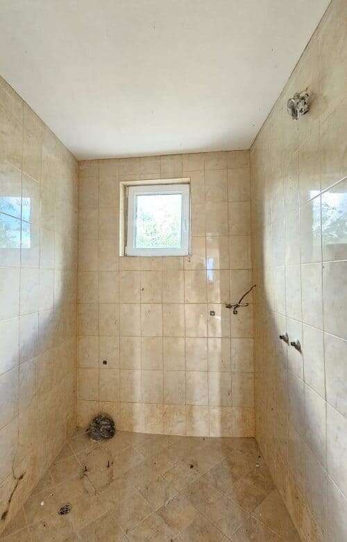 Small bathroom with tiled walls and window in Dyulevo village, Bulgaria.