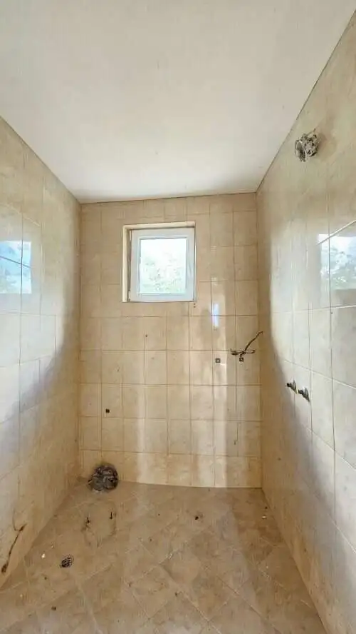 Small bathroom with tiled walls and window in Dyulevo village, Bulgaria.