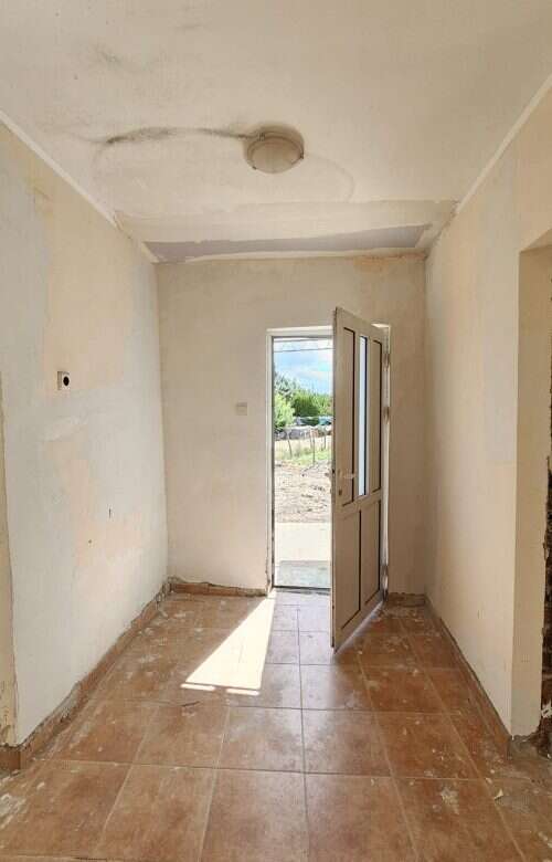 Interior view of a 2-bedroom bungalow in Dyulevo village, showing unfinished walls and a door leadin.