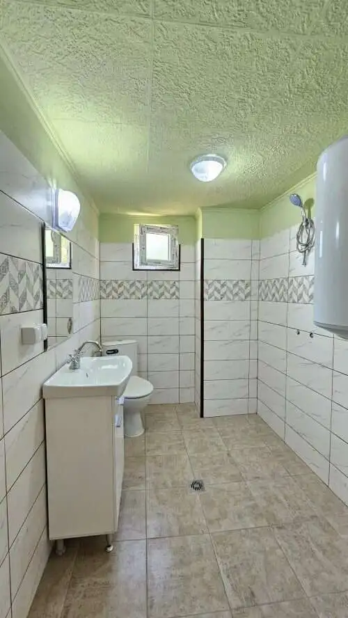Bright renovated bathroom with white sink, toilet, and tiled walls in a spacious home.