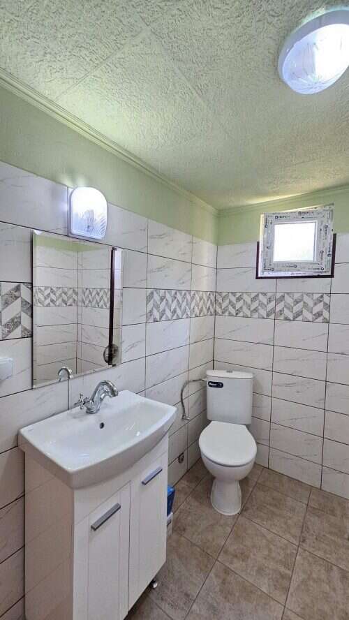 Bright bathroom with new sink, mirror, and toilet in a renovated house.