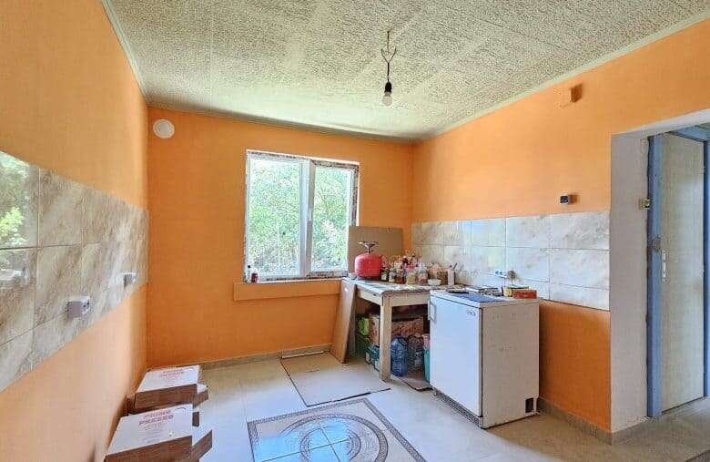 Renovated kitchen with orange walls, large window, and basic appliances in Dyulevo.