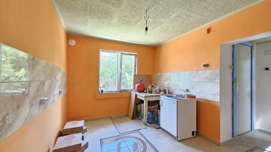 Renovated kitchen with orange walls, large window, and basic appliances in Dyulevo.