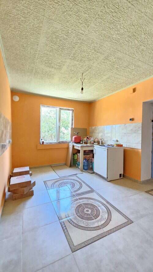 Interior view of a renovated house kitchen in Dyulevo, Bulgaria, with orange walls and a large windo.