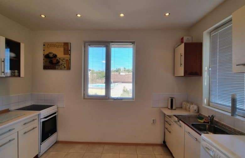 Bright kitchen with white cabinets, stove, and large windows in a cozy home.