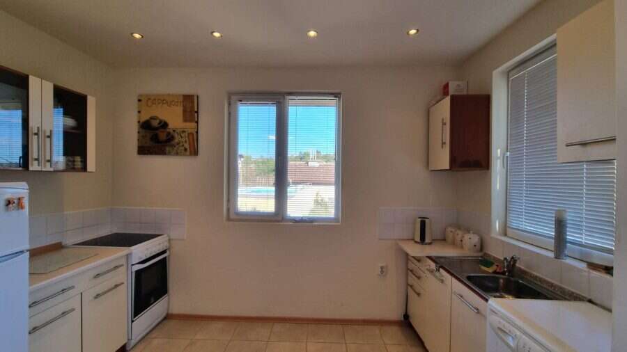 Bright kitchen with white cabinets, stove, and large windows in a cozy home.