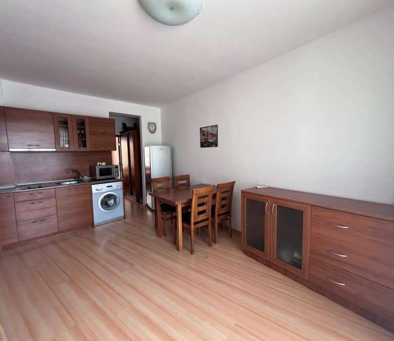 Interior of a 1-bedroom apartment with pool view, wooden furniture, and open kitchen in Sunny Day 3.