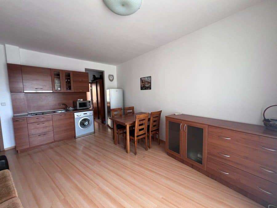 Interior of a 1-bedroom apartment with pool view, wooden furniture, and open kitchen in Sunny Day 3.