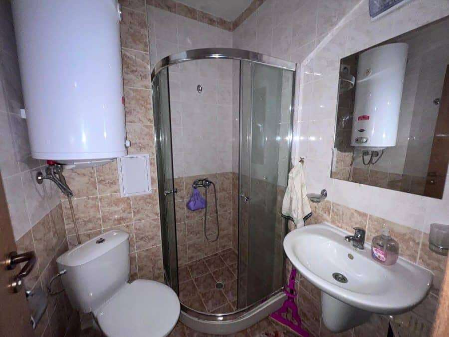 Bright bathroom with shower enclosure, toilet, and sink in Sunny Beach property.