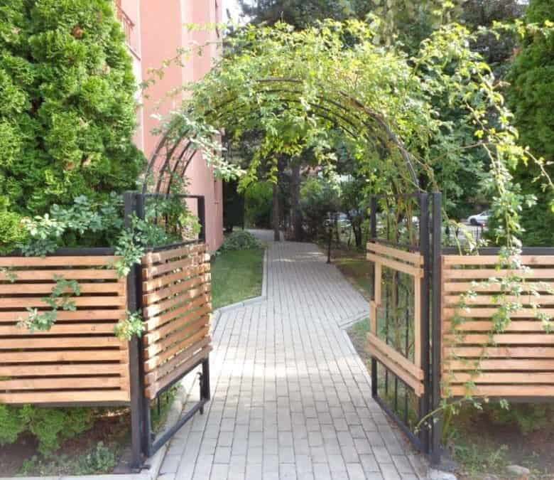 Beautiful garden entrance featuring lush greenery and a decorative arch, leading to a peaceful outdo.