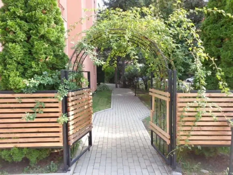 Beautiful garden entrance featuring lush greenery and a decorative arch, leading to a peaceful outdo.