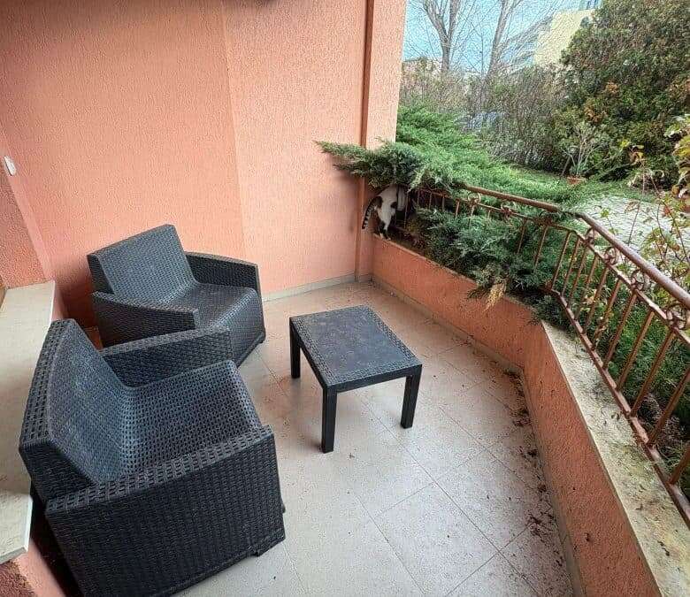 Outdoor balcony with two black wicker chairs and small table in Sunflower complex.