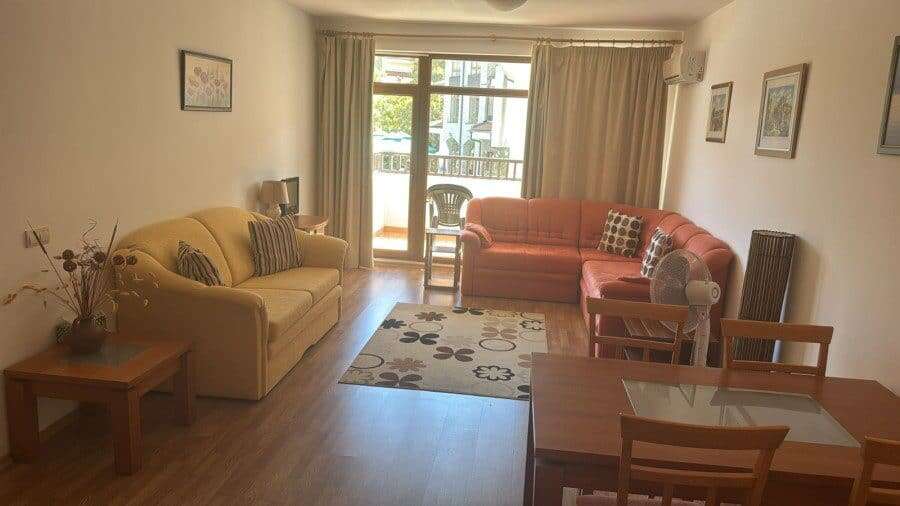 Cozy Living Room with Balcony View Bright living room with sofas and balcony overlooking greenery, near the sea.