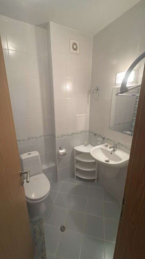 Cozy Bathroom in Furnished Apartment Small bathroom with toilet, sink, and mirror in a furnished apartment.
