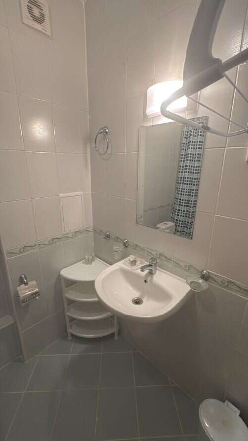 Cozy Bathroom in Furnished Apartment Small bathroom with sink, mirror, and tiled walls in a furnished apartment.