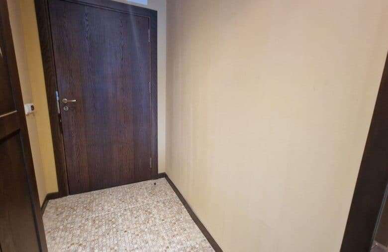 Interior view of a compact studio apartment with wooden door and beige walls in Sunny Beach.