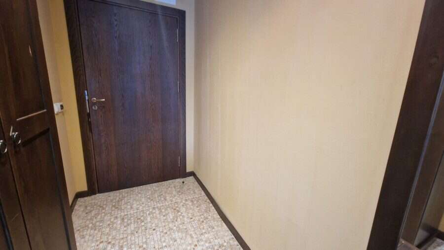 Interior view of a compact studio apartment with wooden door and beige walls in Sunny Beach.