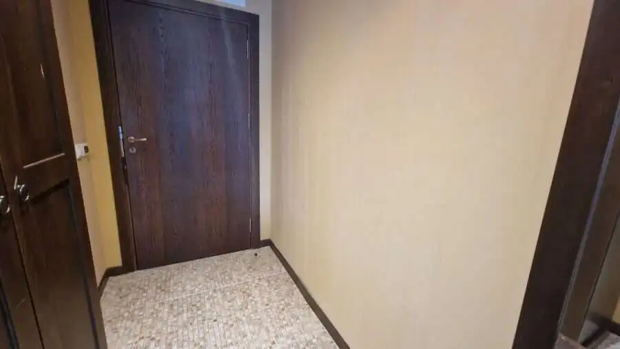 Interior view of a compact studio apartment with wooden door and beige walls in Sunny Beach.
