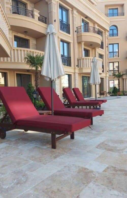 Poolside view of modern apartments at Aphrodite Park in Sunny Beach with sun loungers and umbrellas.